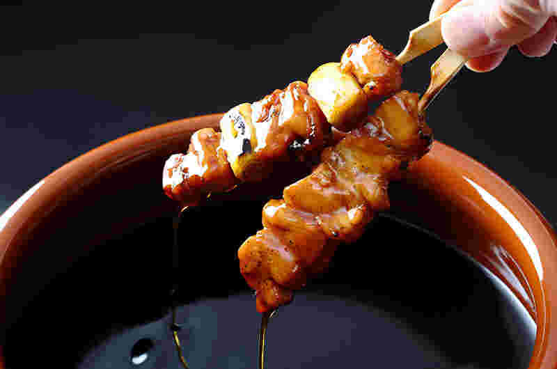 焼き鳥をタレにつけている様子