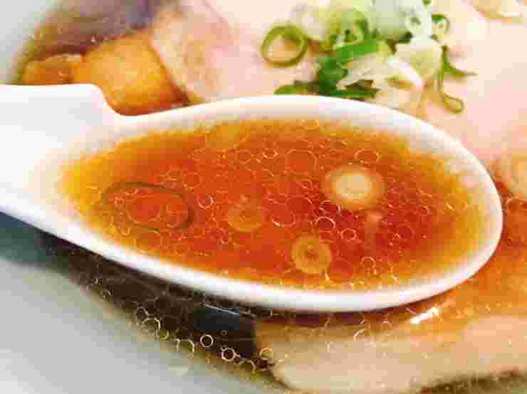 ラーメンのスープをれんげですくう