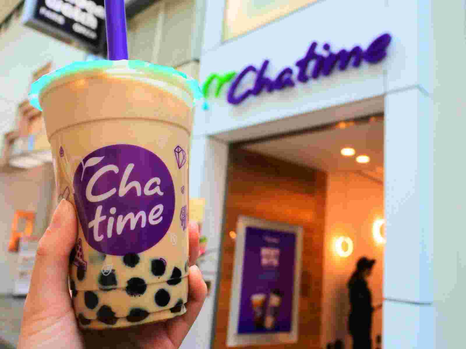 茶タイムの店舗の前でミルクティーをかざしている画像