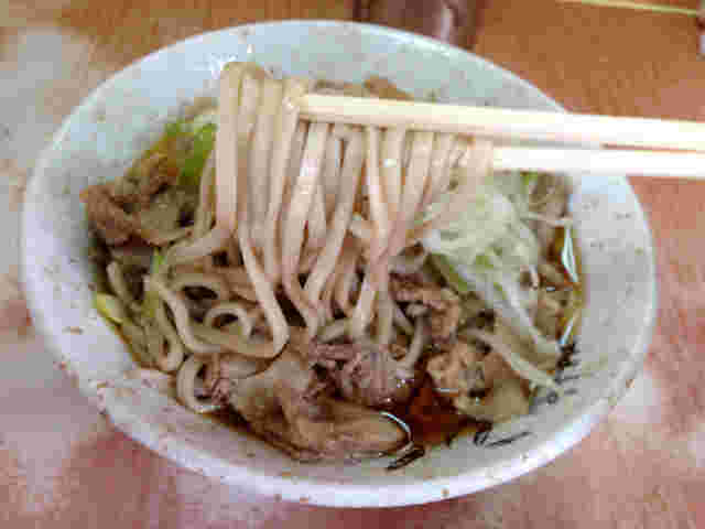 肉そばを箸でつまんでいる様子
