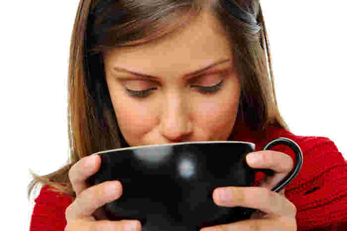 黒いスープカップでスープを飲んでいる女性
