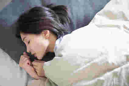 布団の中で眠る女性