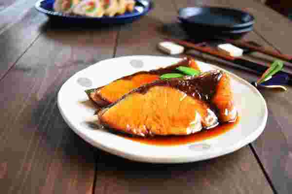 食卓にぶりの照り焼きをのせた皿と箸、他のおかず皿が置かれている