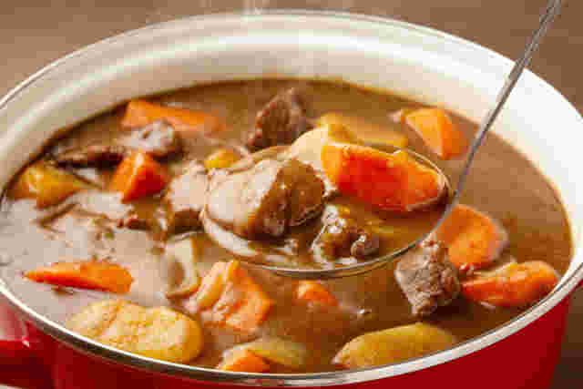赤い鍋に入ったカレーをおたまですくっている様子