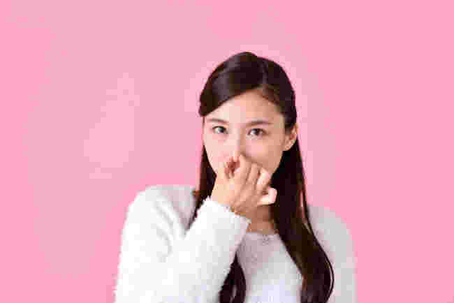 鼻をつまんでいる女性