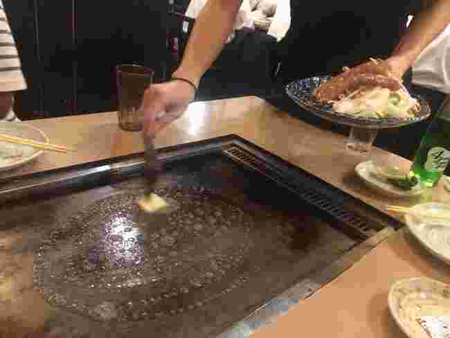 鉄板にバターを敷く店員