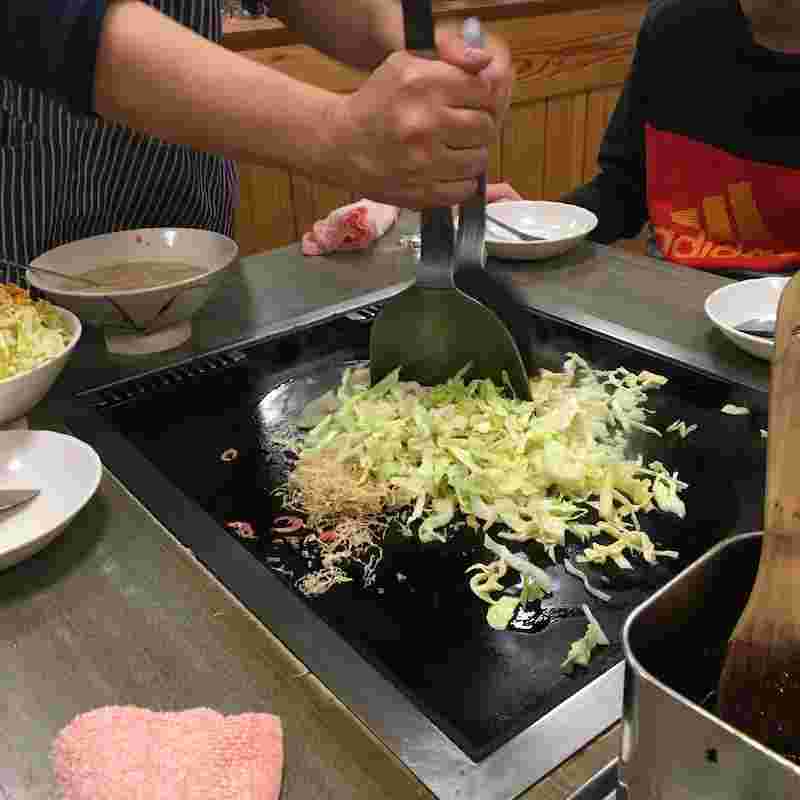 もんじゃの具材をカットしながら炒める様子