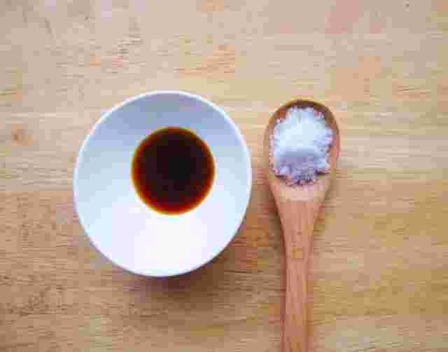 醤油が入った白い器と塩が盛られた木のスプーンが並んでいる様子