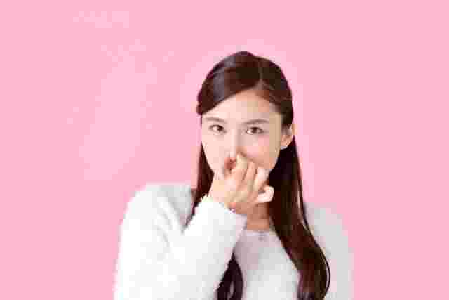 鼻をつまむ女性