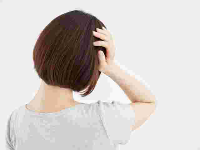 頭痛で頭を押さえる女性