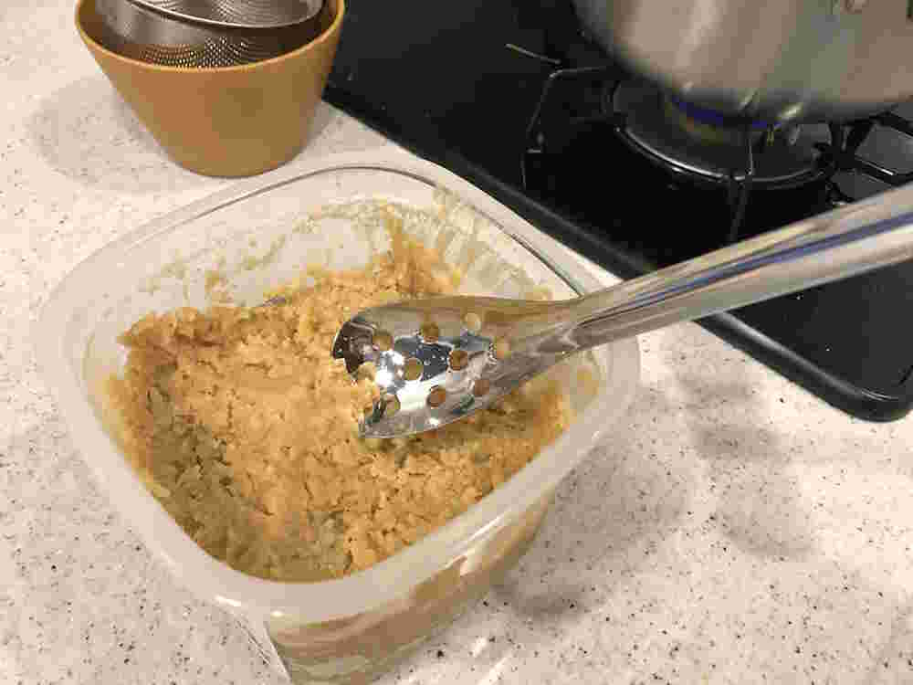 穴の空いたスプーンで味噌をすくうところ