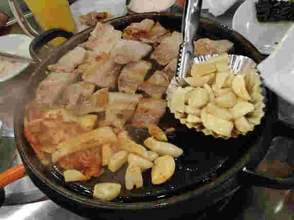 サムギョプサルの肉とキムチとにんにくを焼き上げる様子