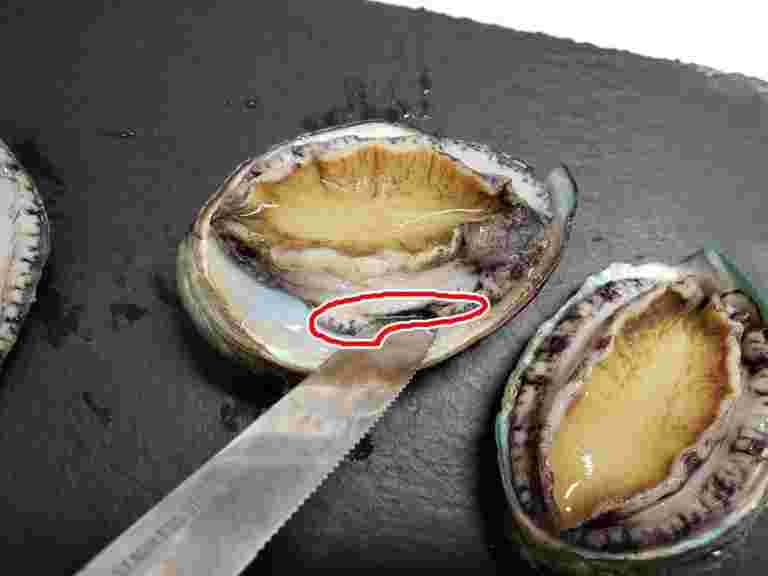 食材の貝の身に包丁を入れている様子。