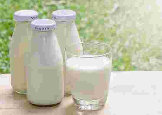 牛乳が入った瓶3本と牛乳が入ったグラス1杯がテーブルの上に並んでいる様子