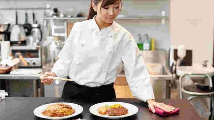 女性シェフが料理を盛り付けている