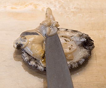 食材の貝の身を包丁で切っている様子。