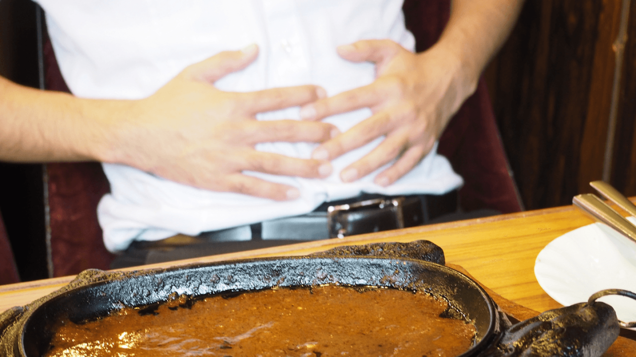 ランチを食べ終わってお腹に手を当てている男性