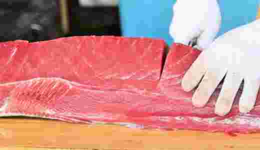 マグロの身のブロックに包丁を入れている様子