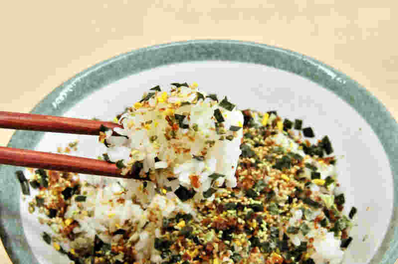 ごはん茶碗に入ったふりかけのかかったごはんを箸で持ち上げている