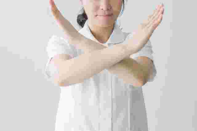 手でバツ印をつくる女性