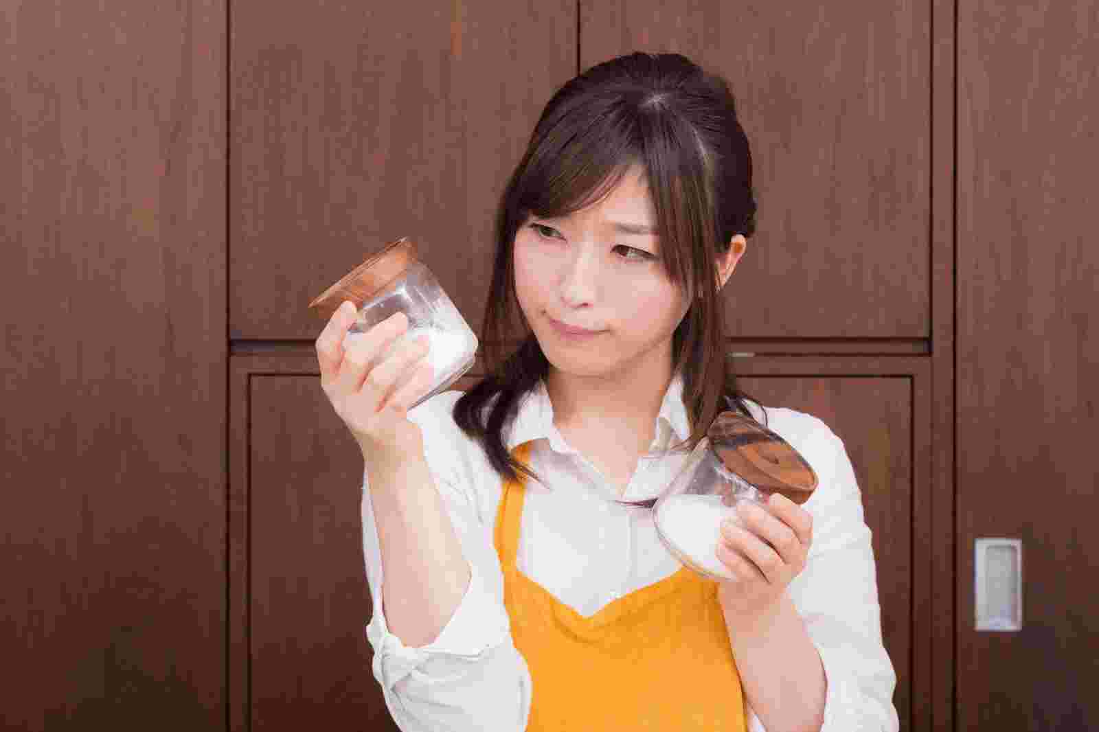 砂糖と塩で悩んでいる女性
