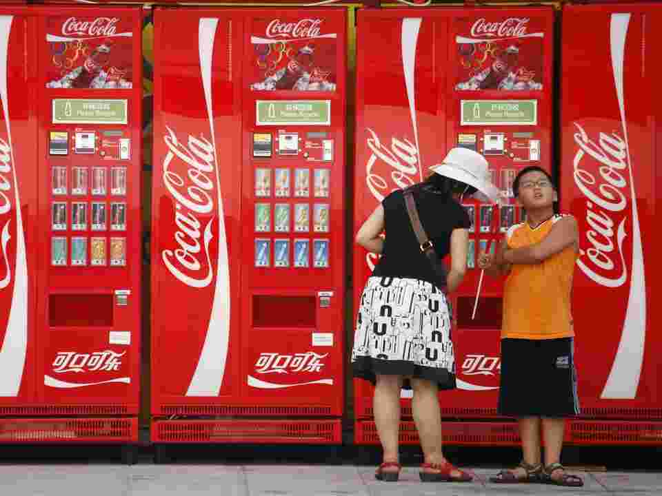 たくさんある自動販売機の前で2人が飲み物を買っている様子。