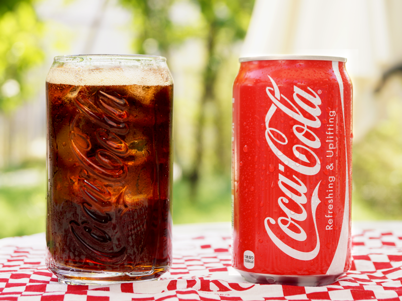 テーブルの上に缶とグラスの飲料水が置いてある模様。