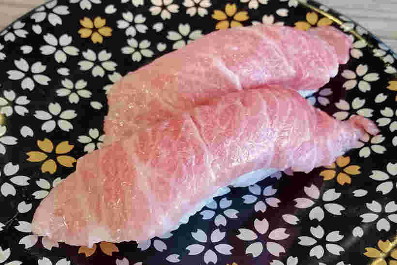 桜柄の皿に脂がたっぷりのった大トロが2貫のっている