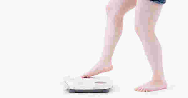 体重計に乗ろうとする女性の足元