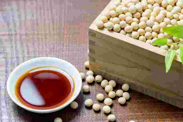 小皿に入れた醤油と木の箱に入った大豆