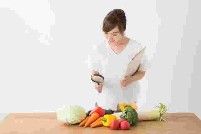虫眼鏡で野菜をみる女性
