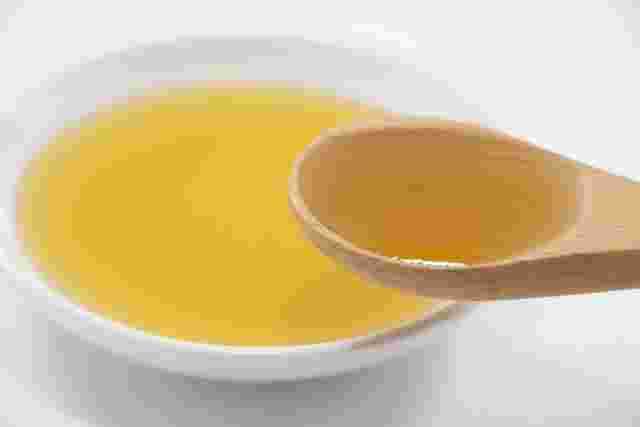 ごま油を木のスプーンにですくっている様子