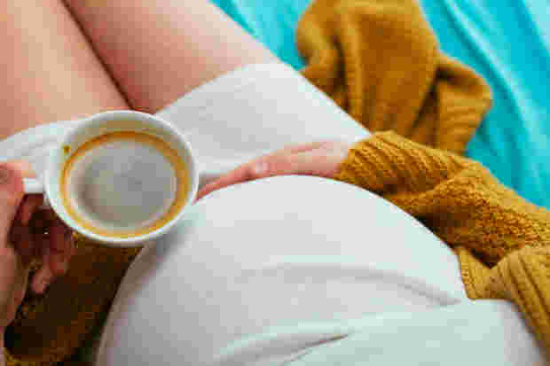 コーヒーカップを持った妊婦さん