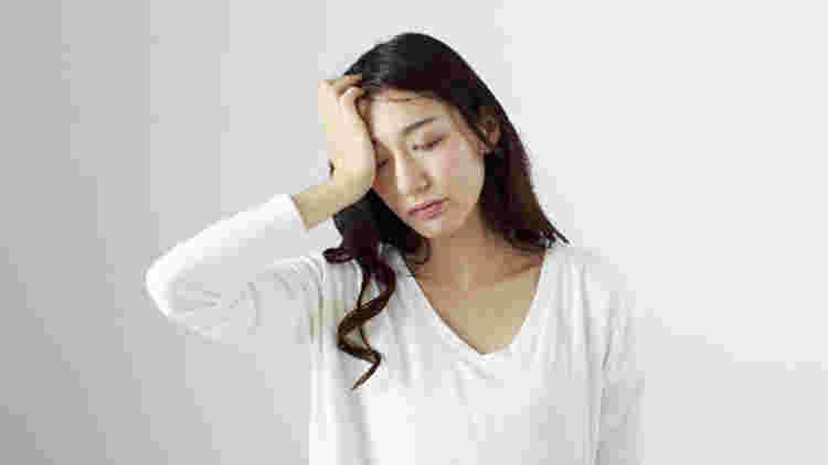 頭を押さえる女性の画像