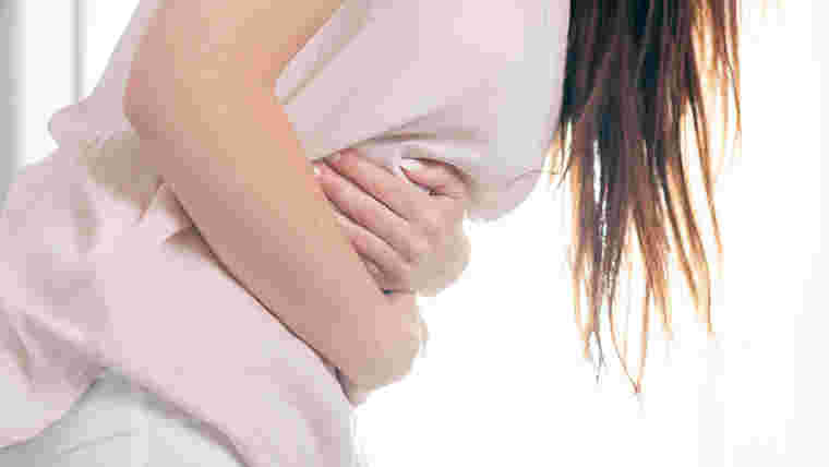 腹痛でお腹を抱える女性
