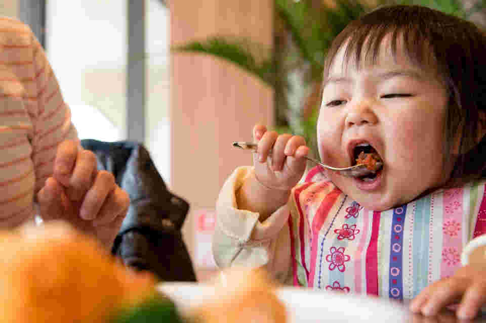 小さな子がレストランで食事をしている