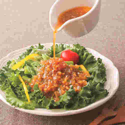 玉ねぎドレッシングを野菜サラダにかけている