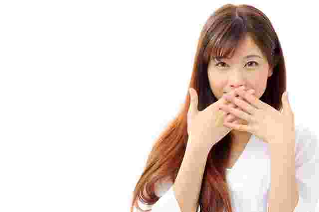 手で口を塞ぐ女性
