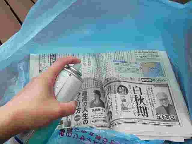 スプレーを新聞紙に向けて噴射しているところ