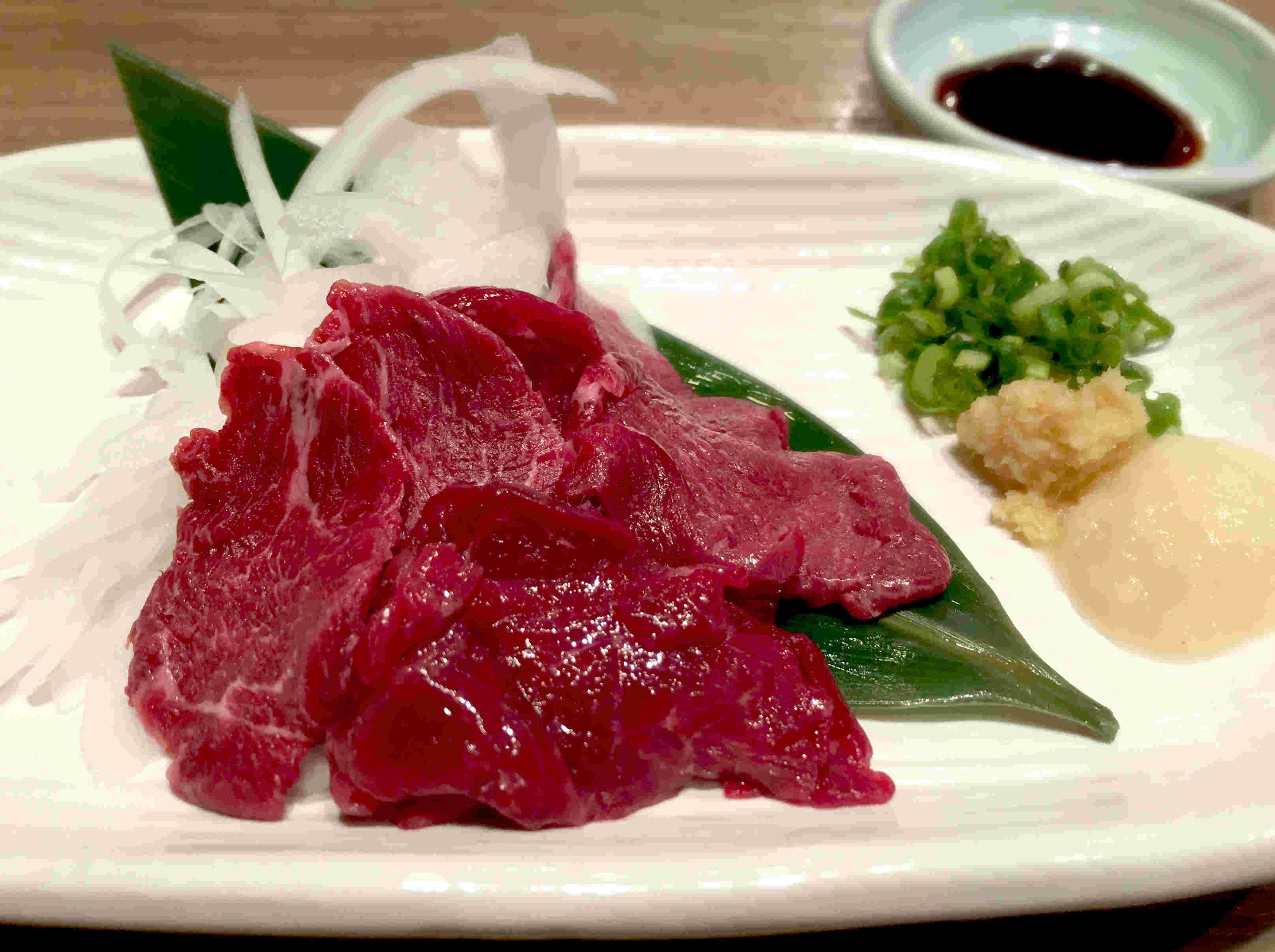 皿に盛りつけられたオニオンスライスと馬刺し