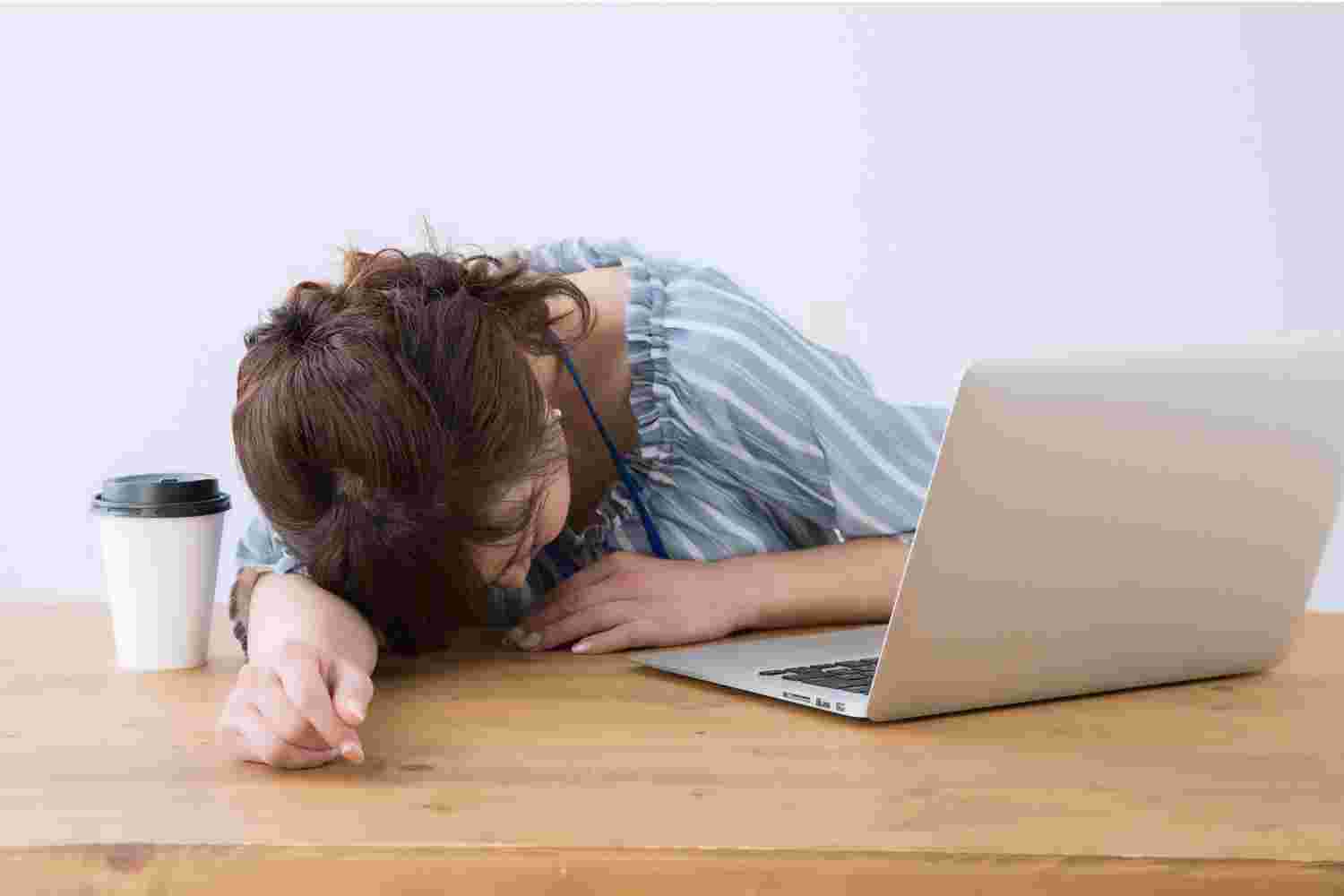 コーヒーを横に仕事中に眠る女性
