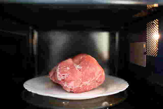 電子レンジに入った賞味期限が切れていない冷凍肉の画像
