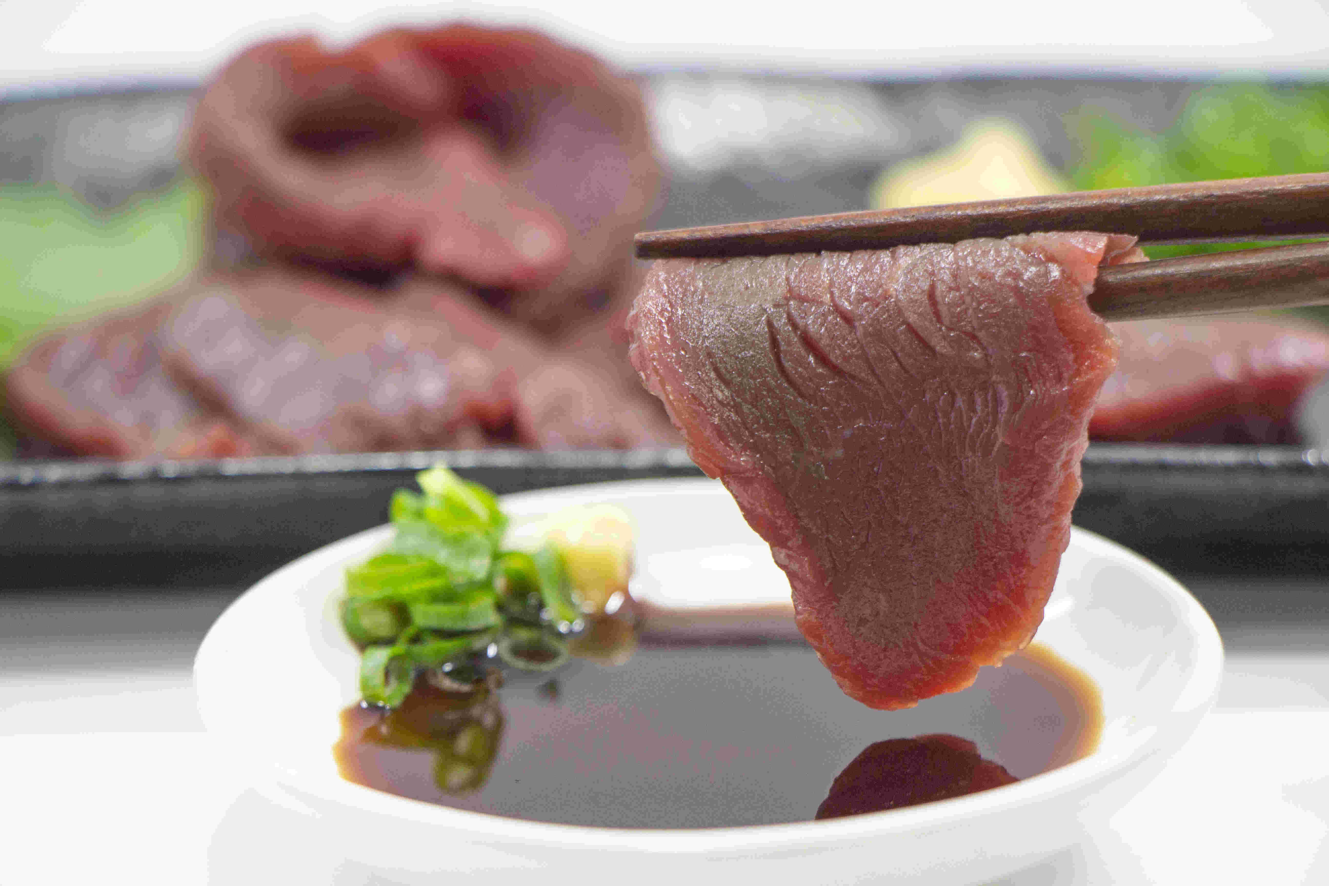 甘口醤油につけ箸で持った馬刺し
