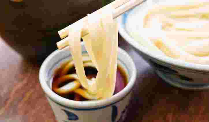 うどんをつゆにつけている画像