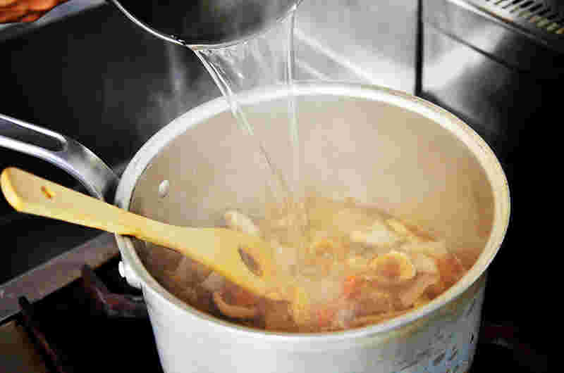 炒めた豚汁の材料に出汁を加えているところ