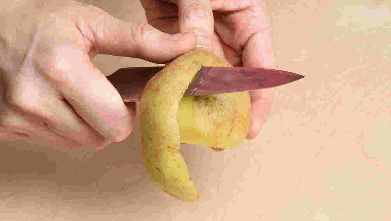 じゃがいもの皮をナイフで剥いているシーン
