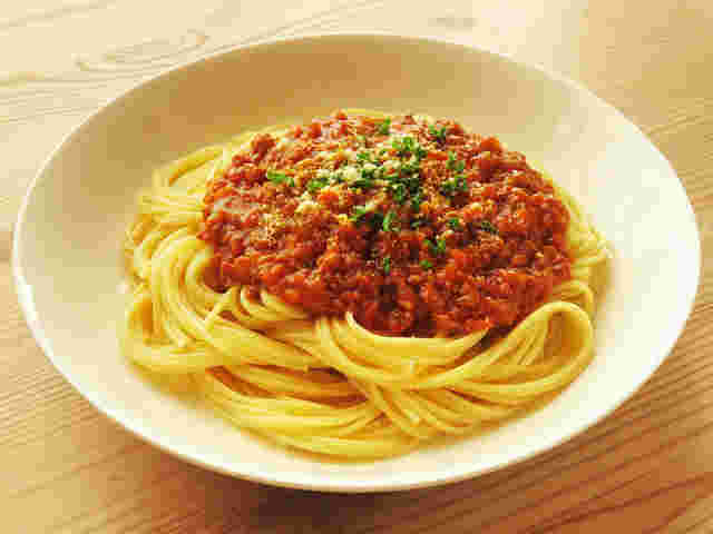ミートソーススパゲティの上にパセリと粉チーズを散らしている