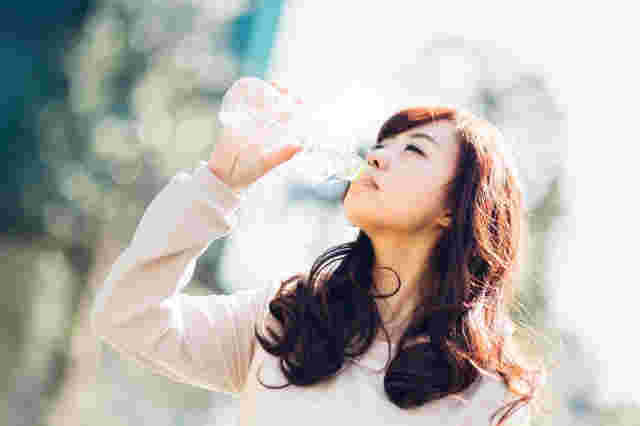 ペットボトルの炭酸水を飲む女性