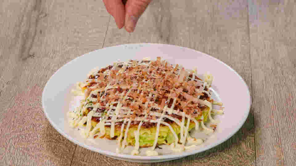 お好み焼きにダイエットに不向きなトッピングをしている画像