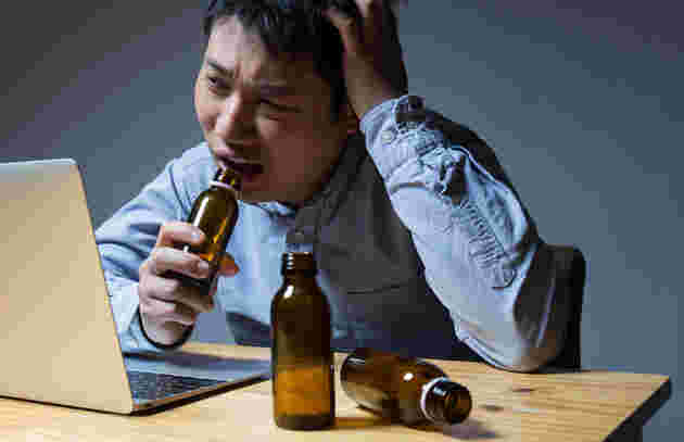 栄養ドリンクを飲んでパソコン作業をしている男性
